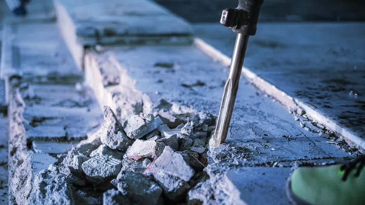 Martelo de demolição quebrando concreto em um canteiro de obras.