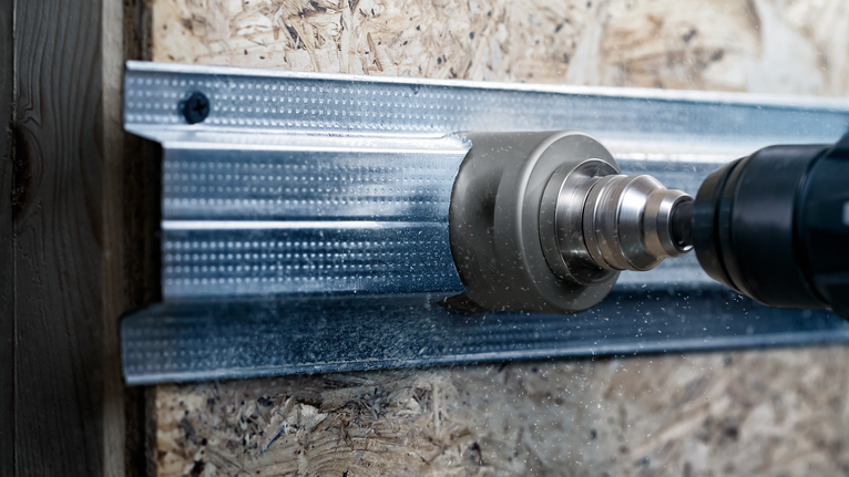 Faça um furo com uma serra copo para cortar uma viga de metal.