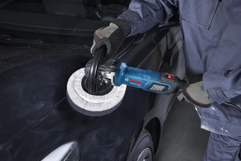 Uma pessoa usando equipamento de segurança usa uma politriz no capô de um carro preto.