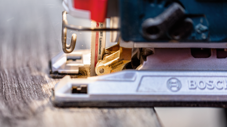 Serra tico-tico cortando uma tábua de madeira.