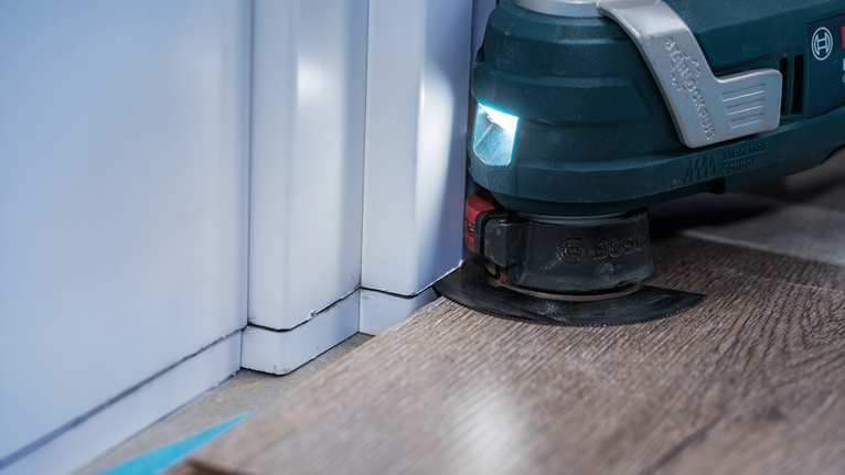 Ferramenta multifuncional oscilante para aparar piso laminado próximo à parede.