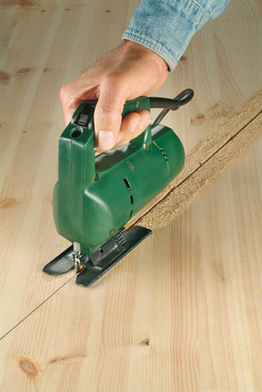 Una persona guía una sierra de calar para cortar una línea recta a través de una tabla de madera.