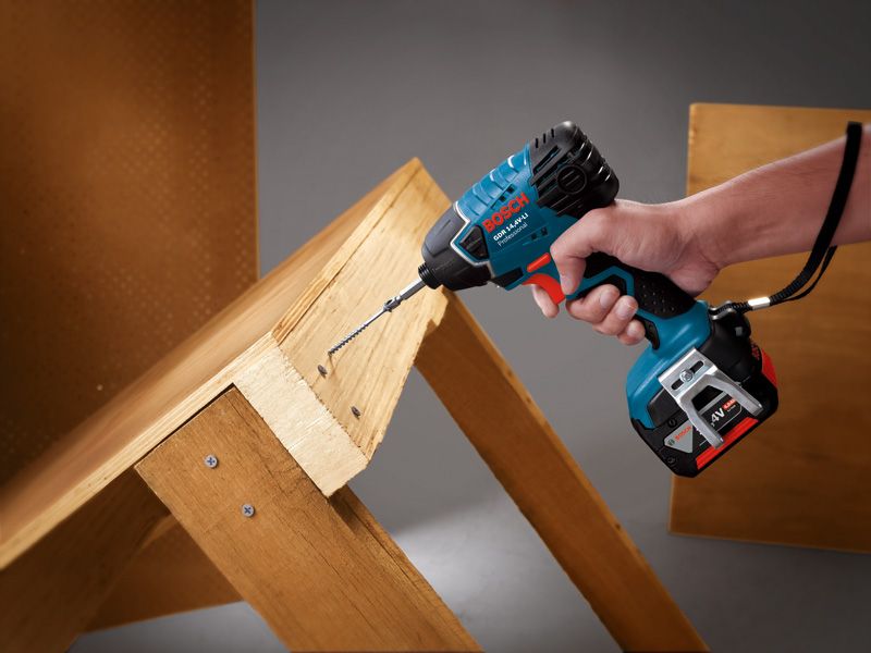 Persona que utiliza un destornillador de impacto inalámbrico para atornillar tornillos en tablas de madera.