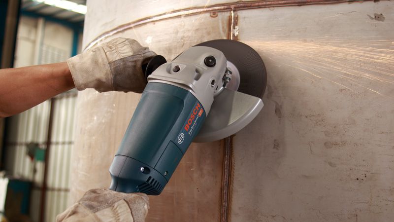 Una persona que usa equipo de seguridad muele una superficie metálica utilizando una amoladora angular.