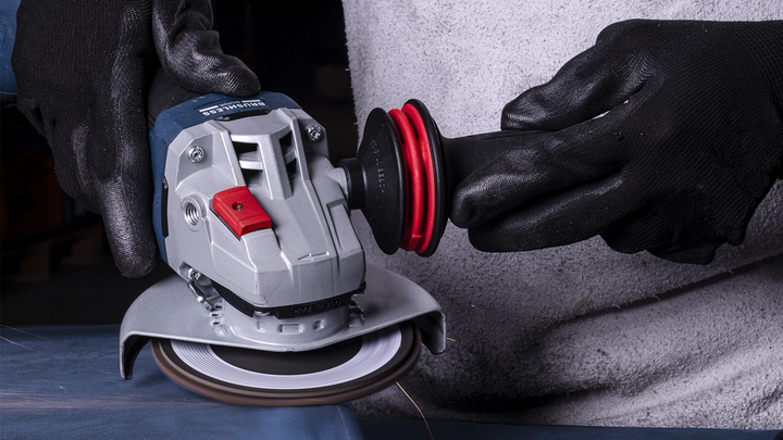 Una persona que usa equipo de seguridad utiliza una amoladora angular para cortar metal.