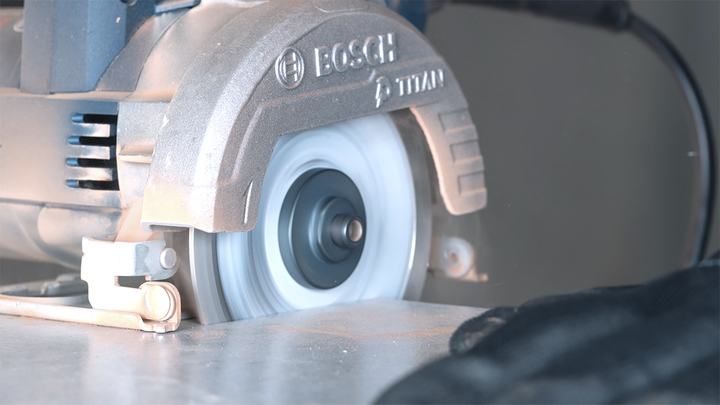 Sierra circular cortando una baldosa en un banco de trabajo.