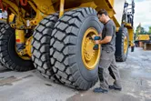 Una persona que usa equipo de seguridad utiliza una llave de impacto en un neumático grande de un vehículo de construcción.
