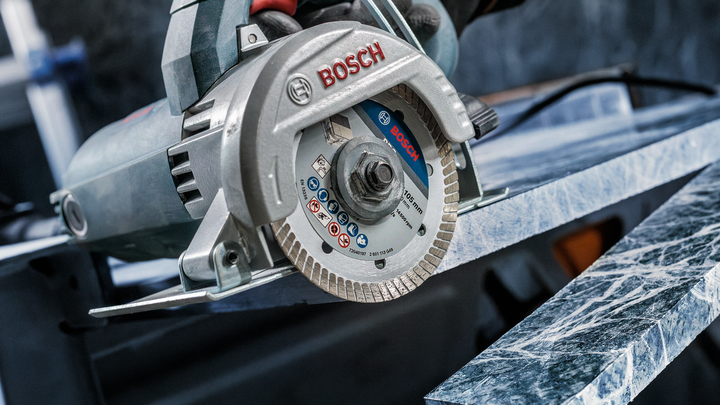 Una persona que usa equipo de seguridad corta una losa de mármol con una sierra circular.