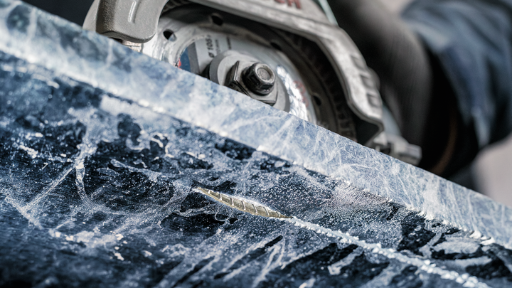 Una persona que usa equipo de seguridad utiliza una sierra circular para cortar piedra.