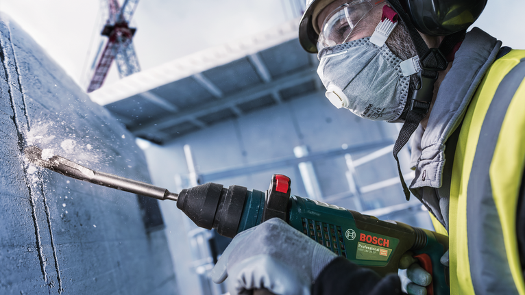 Una persona que usa equipo de seguridad perfora hormigón en una obra en construcción.