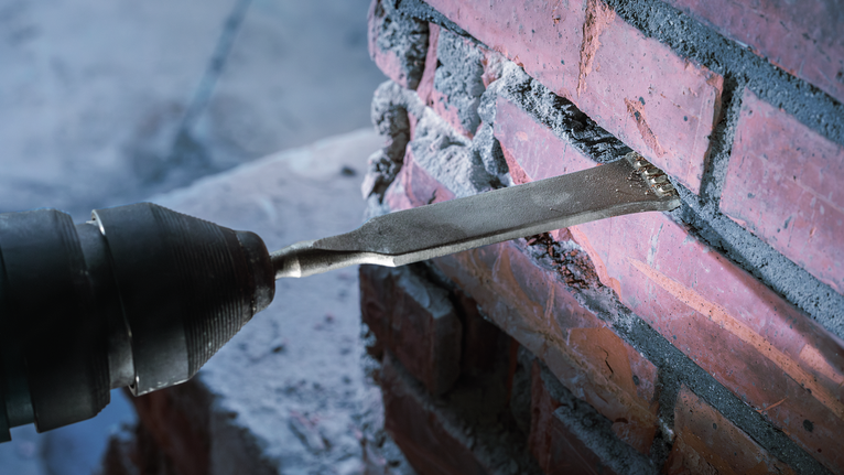 El cincel quita el mortero de la pared de ladrillo durante los trabajos de restauración.