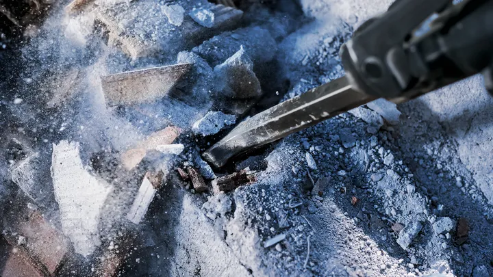 Martillo de demolición rompiendo escombros de hormigón en un sitio de construcción.