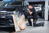 Una persona que usa equipo de seguridad pule el guardabarros de un automóvil en un taller.