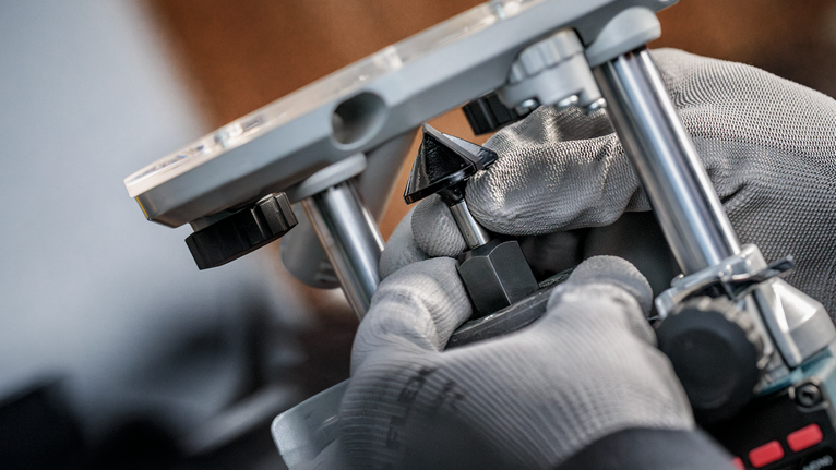 Una persona que usa equipo de seguridad ajusta una broca en una herramienta eléctrica.