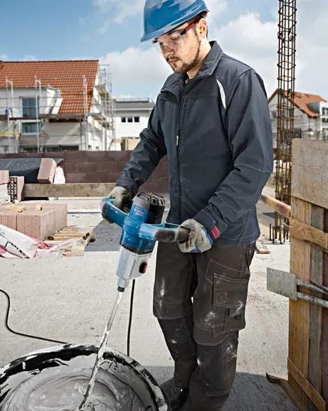 Eine Person mit Schutzausrüstung mischt Material mit einem elektrischen Rührwerk.
