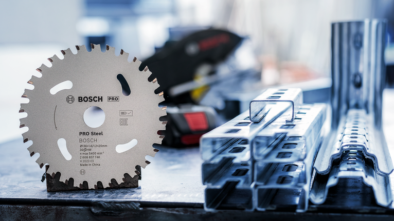 Kreissägeblatt steht aufrecht auf einer Werkbank neben gestapelten Metallträgern.