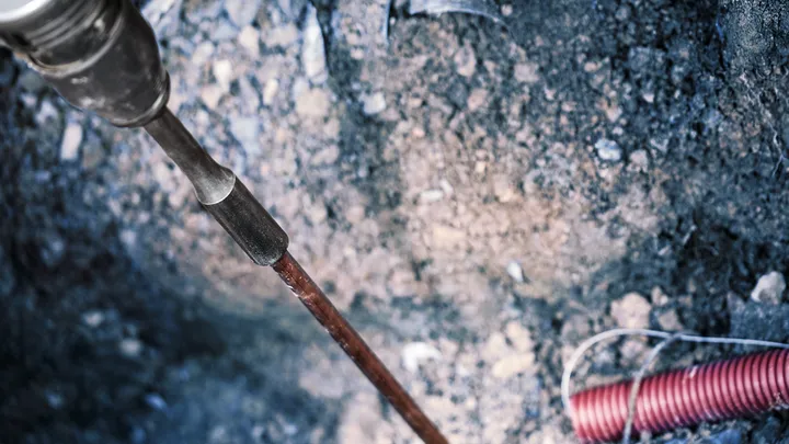 Abbruchhammer durchbricht den Boden auf einer Baustelle.