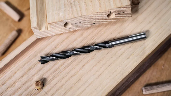 Bohrer auf Holzbrettern mit Dübeln in der Nähe platziert.