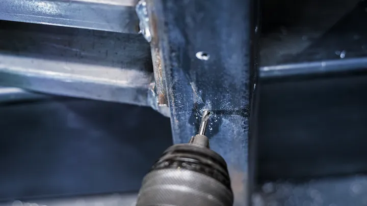 Eine Bohrmaschine, die eine Schraube in einen Metallrahmen treibt.