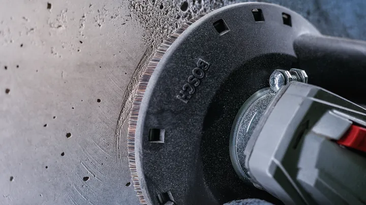 Winkelschleifer schneidet Betonwand, Staub entlang der Kante sichtbar.