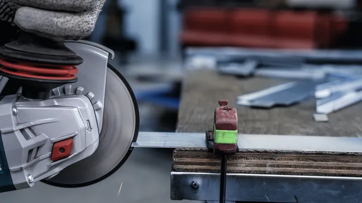 Eine Person mit Sicherheitsausrüstung schneidet Metall mit einer Kreissäge.