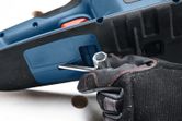 Eine Person mit Sicherheitsausrüstung stellt eine Akku-Kettensäge mit einem Schraubenschlüssel ein.