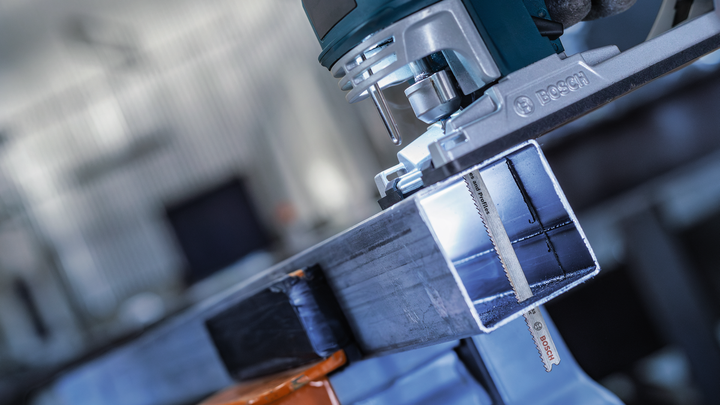 Ein Elektrowerkzeug schneidet in einer Werkstatt durch einen Metallträger.