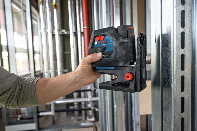 Eine Person positioniert ein Zubehörteil für ein Lasernivellierungswerkzeug an einem Metallrahmen auf einer Baustelle.