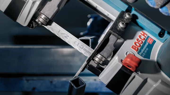 Eine Metallbandsäge schneidet in einer Werkstatt durch ein Vierkantstahlrohr.