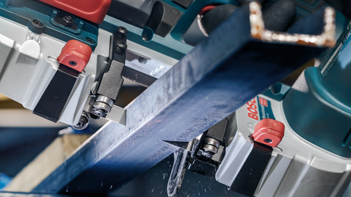 Metallträger werden in einer industriellen Umgebung mit einer Motorsäge präzise geschnitten.