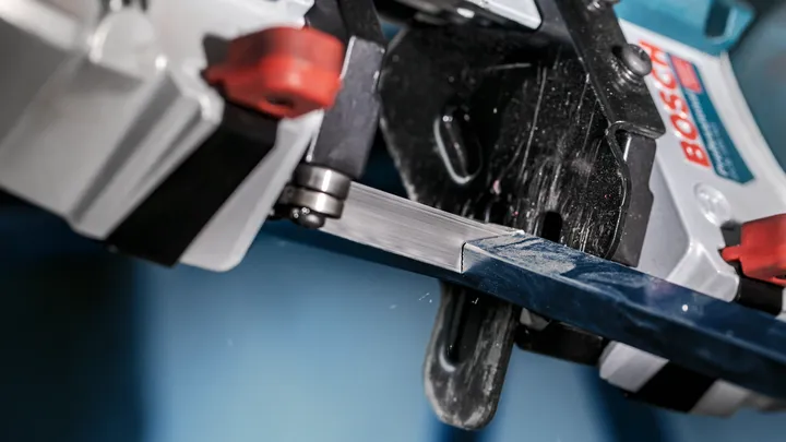 Bandsäge schneidet durch eine Metallstange in einer industriellen Nahaufnahme.