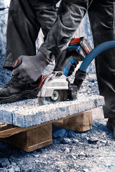 Eine Person mit Schutzausrüstung schneidet Beton mit einem Akku-Winkelschleifer.