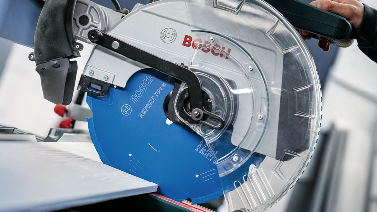 Eine Person, die Schutzausrüstung trägt, bedient eine Kreissäge zum Schneiden eines Metallblechs.