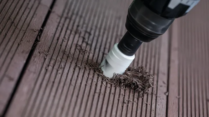 Ein Elektrowerkzeug mit Lochsägenaufsatz bohrt in eine Holzdeckoberfläche.