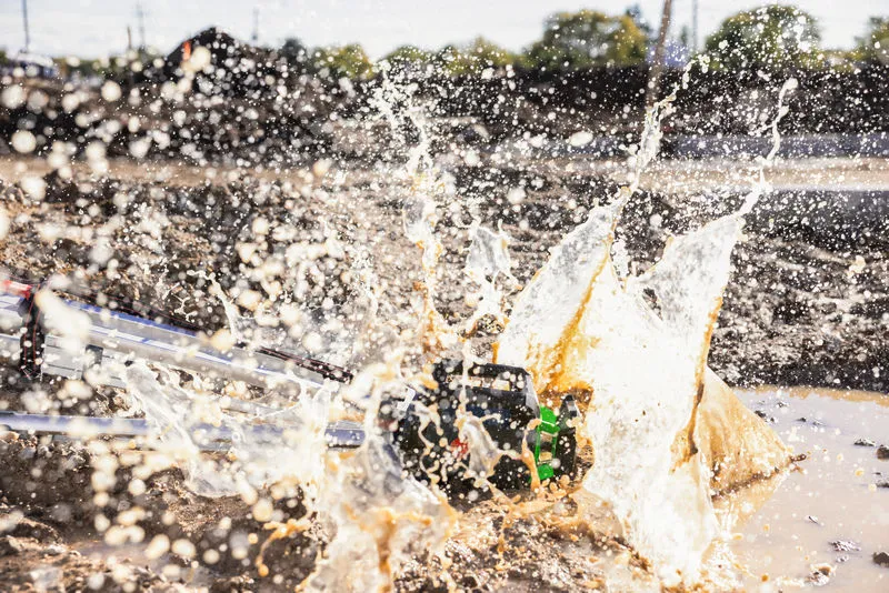 Ein Laser-Nivelliergerät wird auf einer Baustelle von Schlammwasser bespritzt.