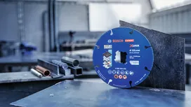 Eine Metalltrennscheibe steht aufrecht auf einem Stahlblech in einer Werkstatt.