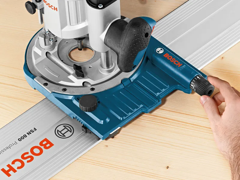 Une personne ajuste un guide de piste d'accessoire de système sur une surface en bois.