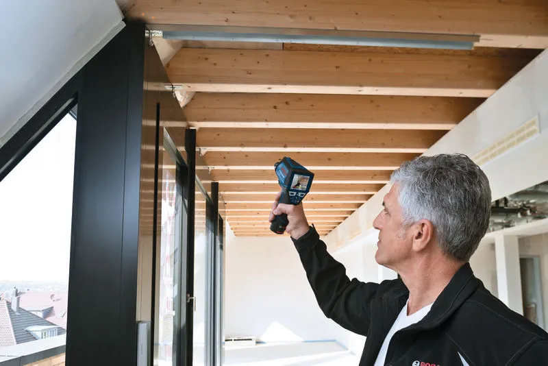 Une personne scanne les poutres du plafond avec un appareil d’inspection portatif.