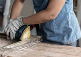 Ponceuse orbitale Bosch lissant une planche de bois.