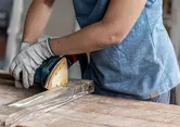 Ponceuse orbitale Bosch lissant une planche de bois.