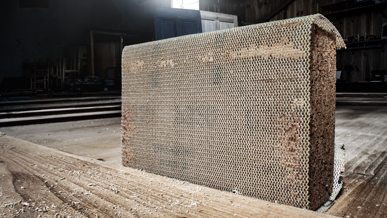 Une section de bois composite à structure en nid d'abeille avec de la sciure sur le sol.