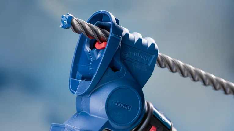 Gros plan d'un accessoire d'outil électrique bleu tenant un foret à maçonnerie.