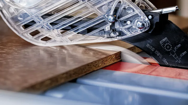 Scie circulaire coupant une planche de bois dans un atelier.