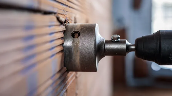 Perçage à la scie cloche dans un mur carrelé à l'intérieur.