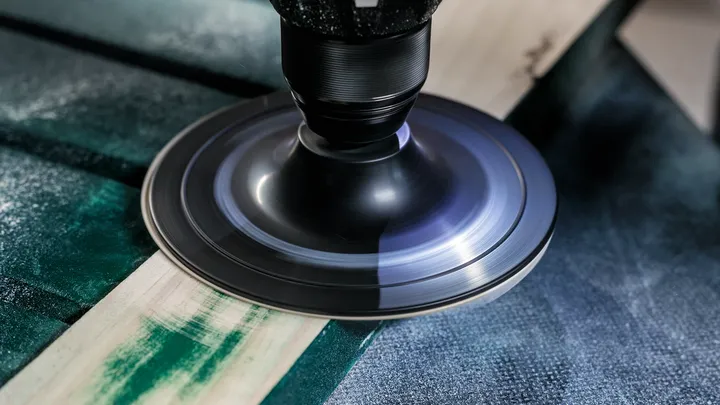 Ponceuse rotative lissant la surface d'une planche de bois.