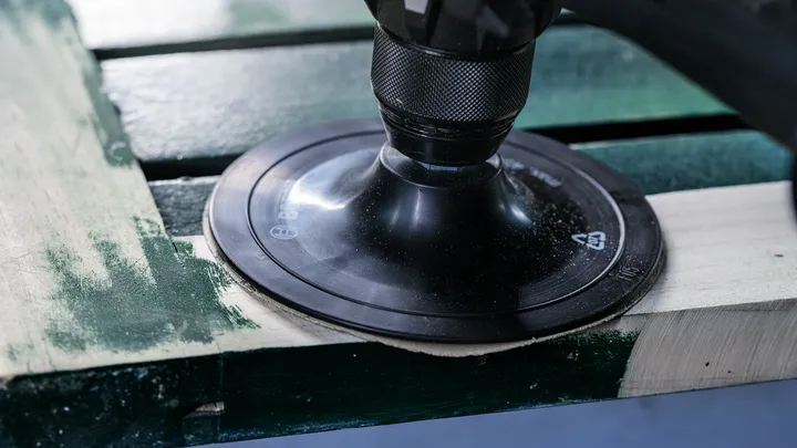 Ponceuse rotative lissant une planche de bois.