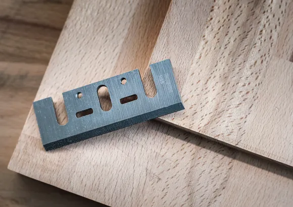 Lame de coupe en métal reposant sur une planche de bois.