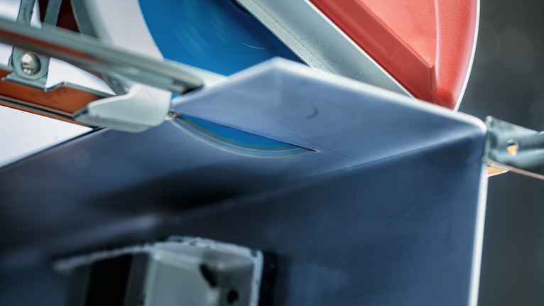 Une scie circulaire coupe une poutre métallique dans un atelier.