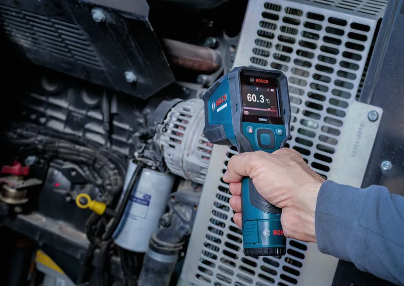 Une personne utilise un détecteur thermique pour mesurer la température des machines industrielles.