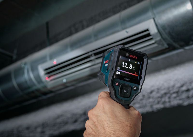 Une personne utilise un détecteur thermique pour vérifier la température d'un système de conduits d'air.